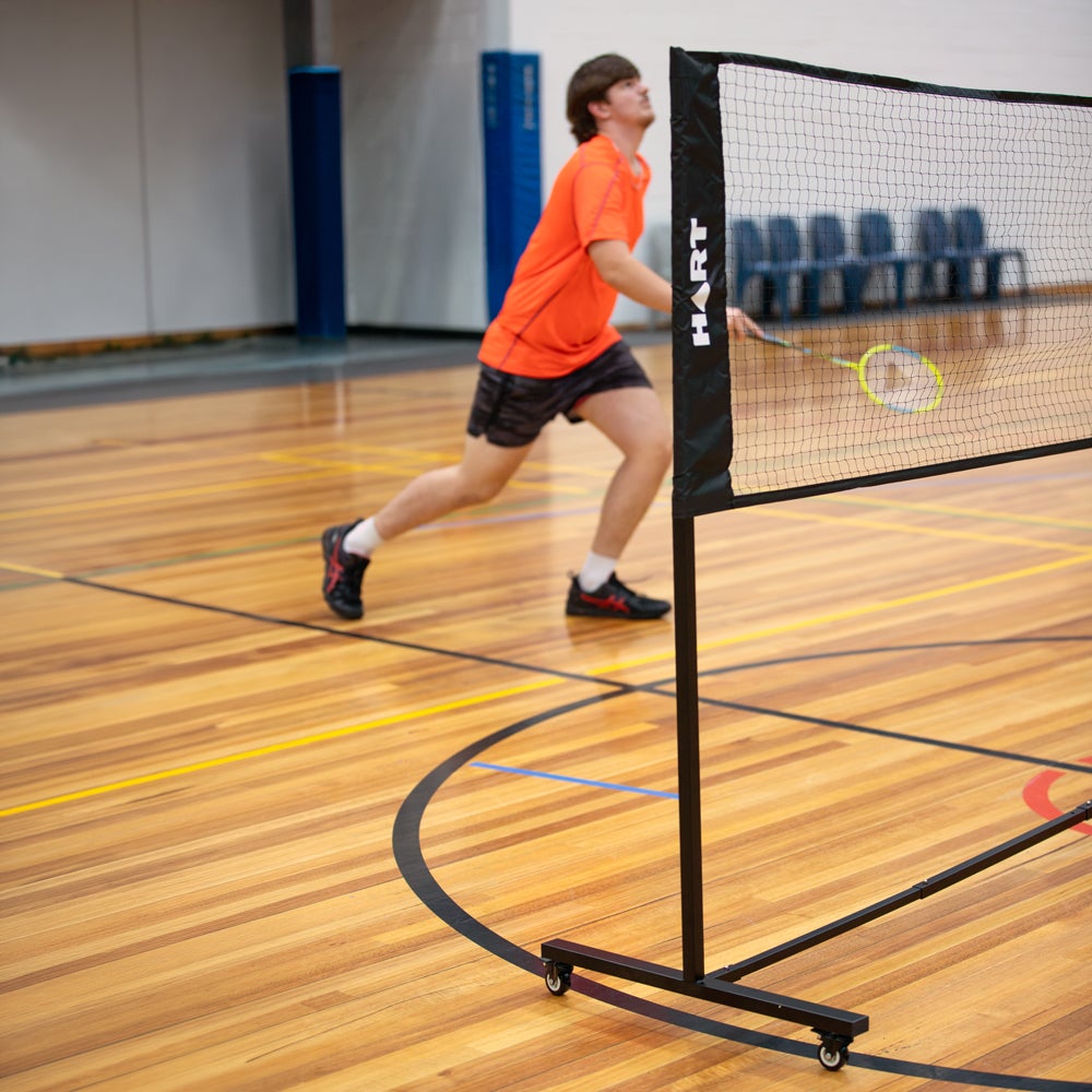 HART Sport rolling badminton net system with sturdy posts and net, designed for easy setup and portable use.