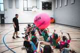 HART official pink KIN-BALL fun ball being tossed in a corridor, featuring vibrant pink color and durable rubber exterior.