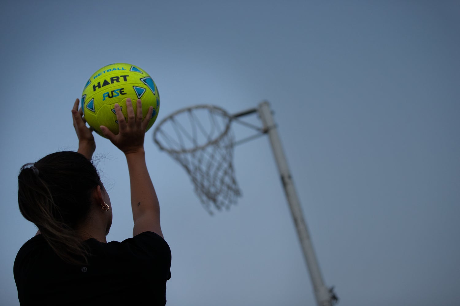 HART Fuse Netball with orange and white panels, designed for outdoor play and training, featuring durable synthetic material.