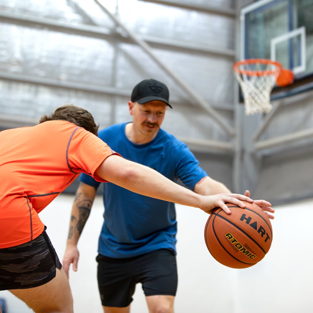 HART Atomic Basketball showing the orange rubber surface and black textured grip for outdoor play.