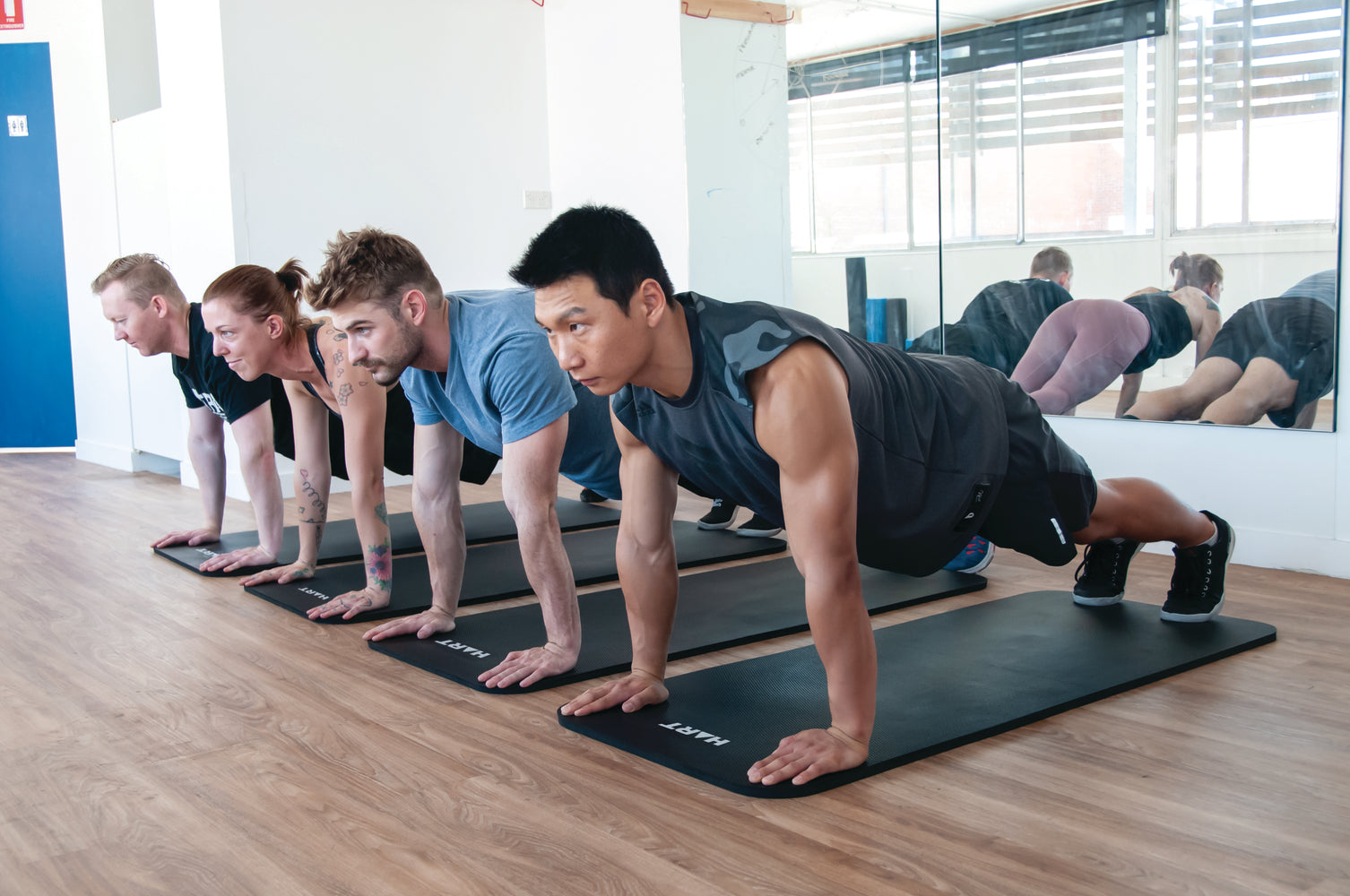 HART workout mat pack with six colorful exercise mats laid out on a wooden floor for fitness training.