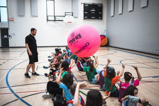 HART official pink KIN-BALL fun ball being tossed in a corridor, featuring vibrant pink color and durable rubber exterior.